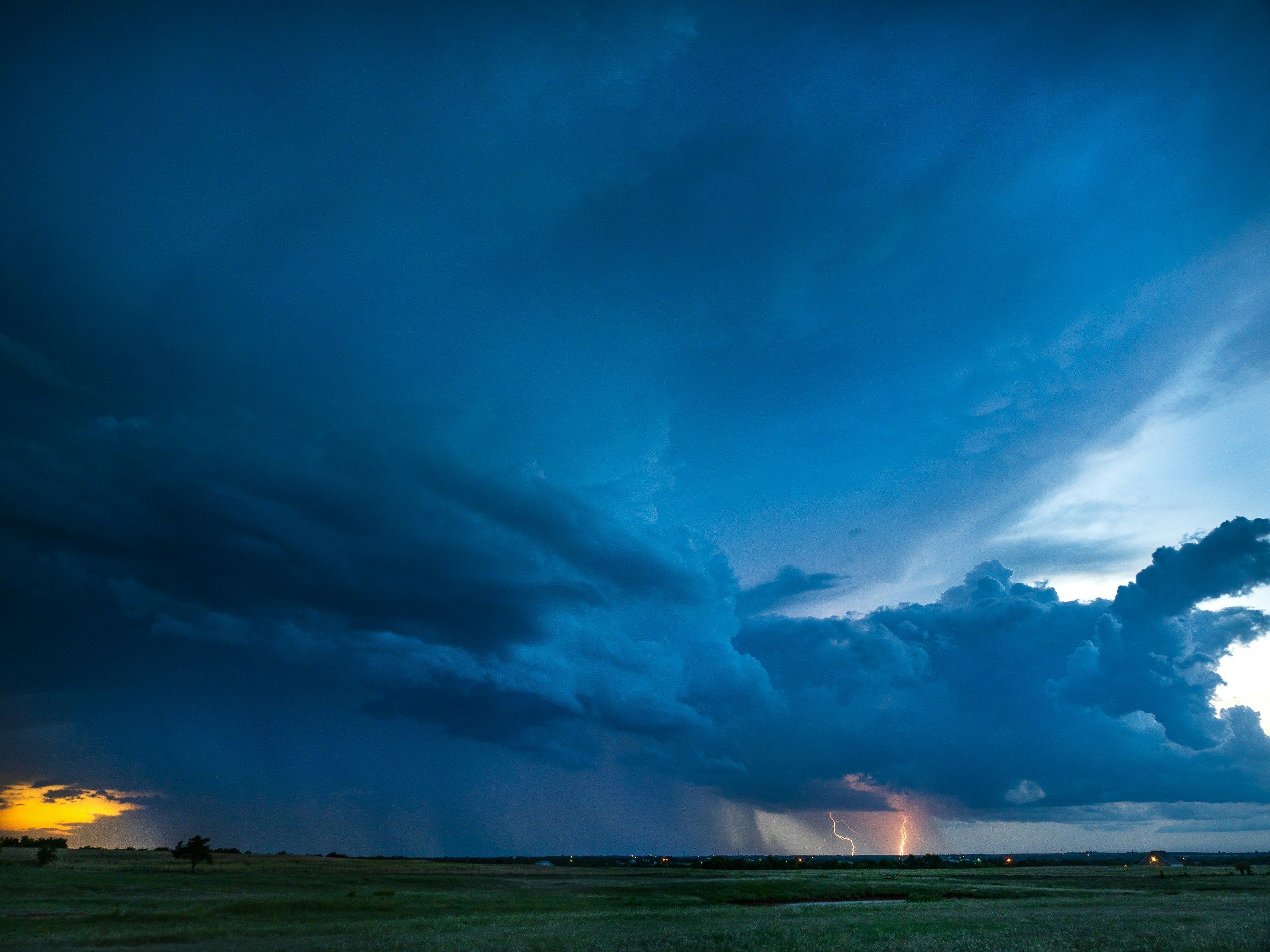 Storm clearing at blue hour with lightning and rain shafts under a breaking sky