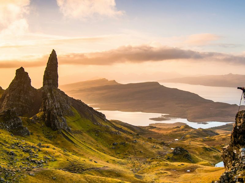 Photographer on a mountain peak shooting golden hour light with scattered clouds at sunset
